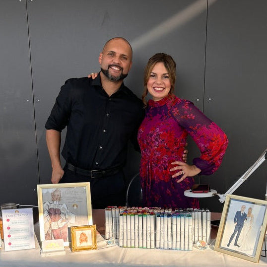 Two people standing behind a table with photo albums and framed pictures.
