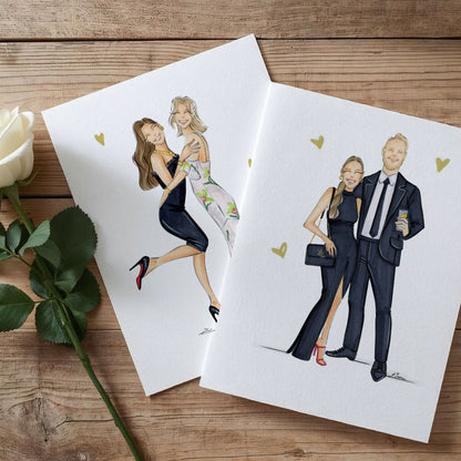 Two papers with fashion illustrations of couples on a wooden surface with a white rose.
