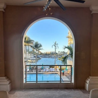 Living room with a large arched window overlooking a waterfront view.